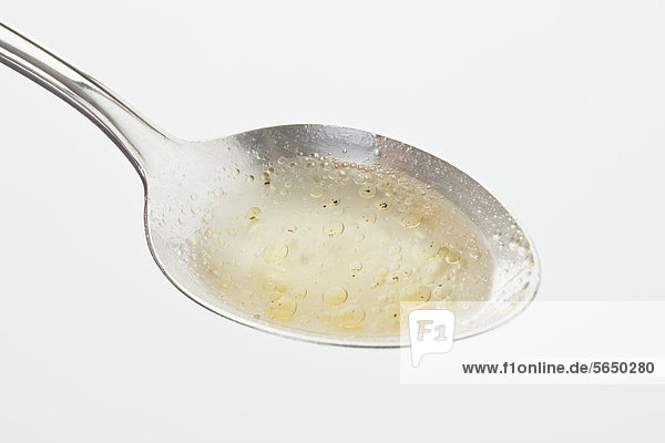 Chicken soup in spoon against white background