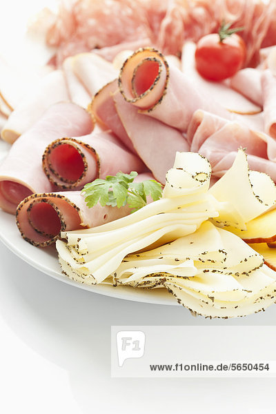Verschiedene Fleisch- und Käsescheiben im Teller auf weißem Hintergrund