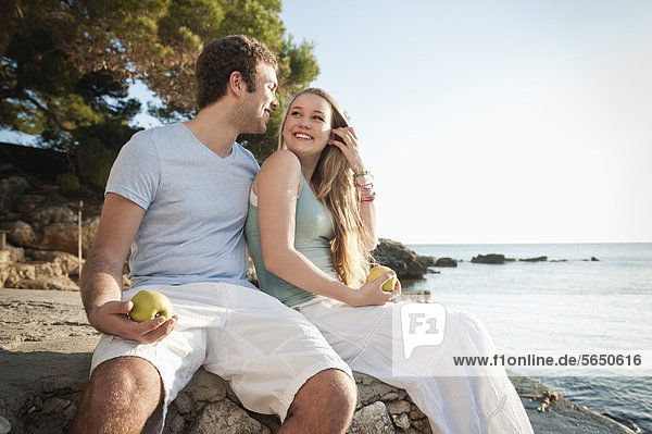 Spain  Mallorca  Couple sitting on beach  smiling