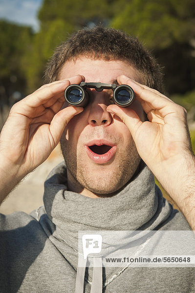 Spain  Mallorca  Young man looking through binocular