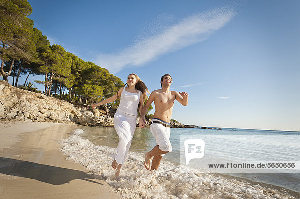 Spanien  Mallorca  Paar läuft am Strand entlang