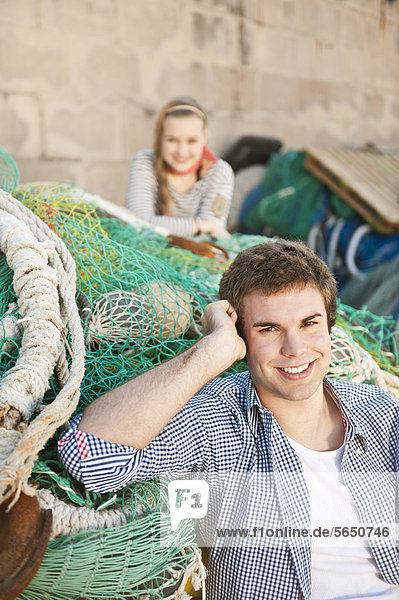 Spanien  Mallorca  Paar am Hafen mit Fischernetzen  lächelnd  Portrait