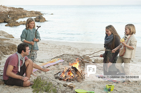 Spanien  Mallorca  Freunde beim Würstchengrillen am Lagerfeuer am Strand