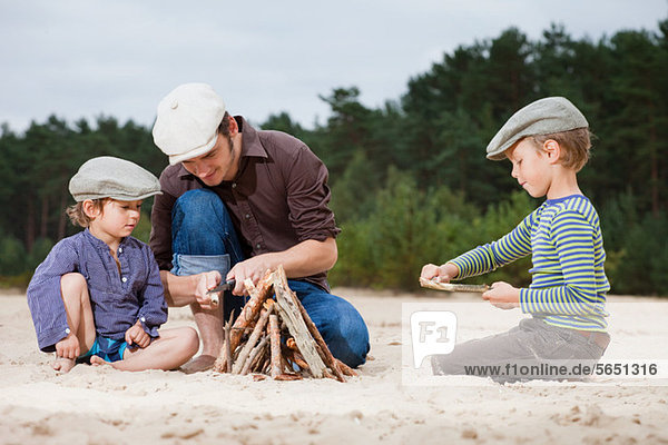 Father and sons making a bonfire on beach