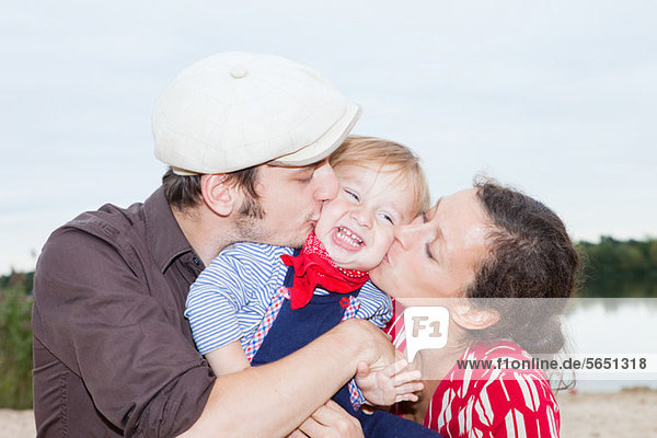 Couple kissing their young son on his cheeks