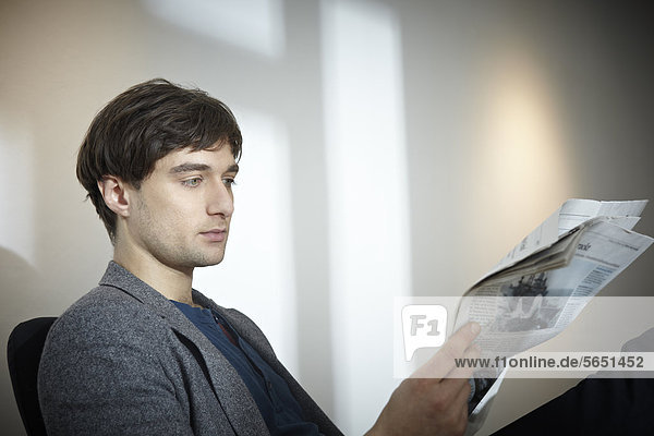 Mid adult man reading newspaper