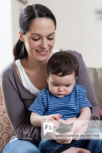 Mother and baby boy holding remote control