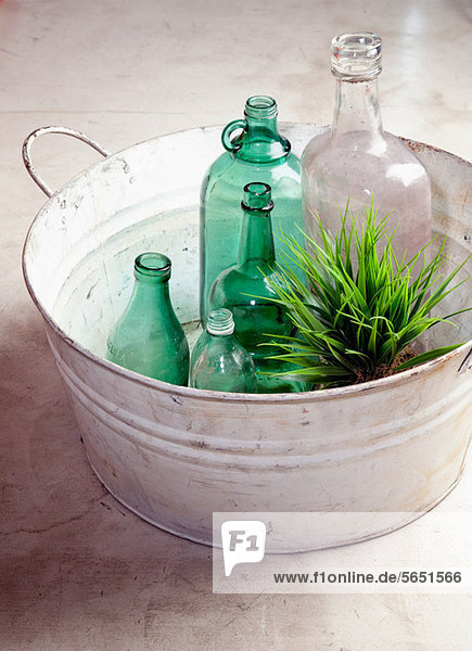 Flaschen und Pflanzen in einem alten Bottich