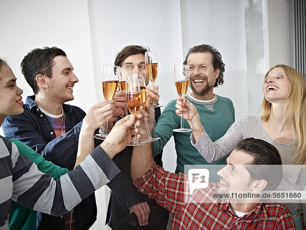 Men and women toasting with champagne in office