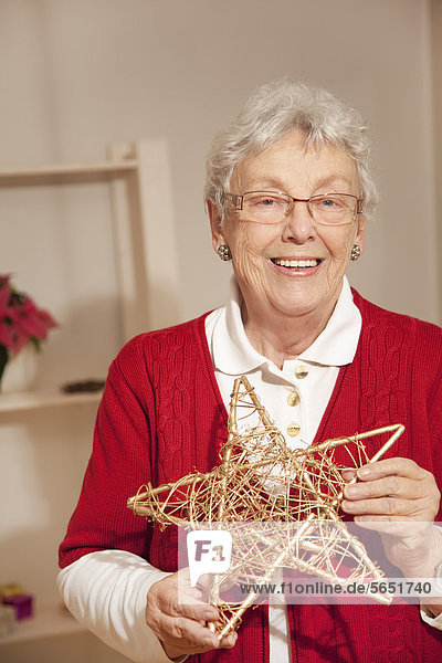 Senior woman holding star during christmas  smiling  portrait