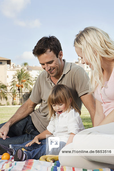 Spanien  Mallorca  Palma  Familie auf Decke sitzend  lächelnd