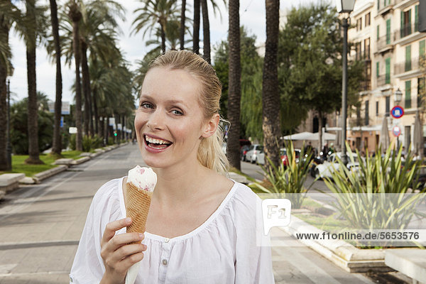 Spanien  Mallorca  Palma  Junge Frau beim Eis essen  lächelnd  Portrait