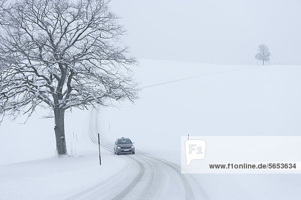 Deutschland  Oberbayern  Blick auf das Auto auf verschneiter Straße
