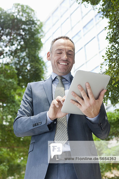 Deutschland  Leipzig  Geschäftsmann mit digitalem Tablett  lächelnd