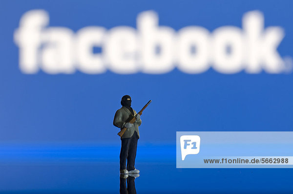 Islamist mit Waffe  Miniaturfigur vor unscharfem Facebook-Logo  Symbolbild