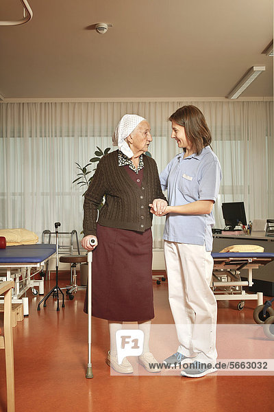 Alte Frau mit Pflegerin bei der Physiotherapie im Pflegeheim