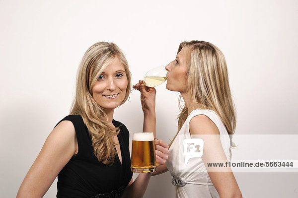 Twin sisters  one with a beer mug  the other with a wine glass