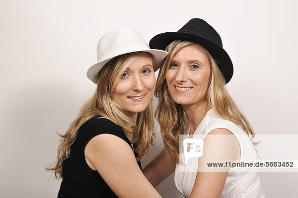 Twin sisters wearing hats in black and white in opposite colors to their clothes