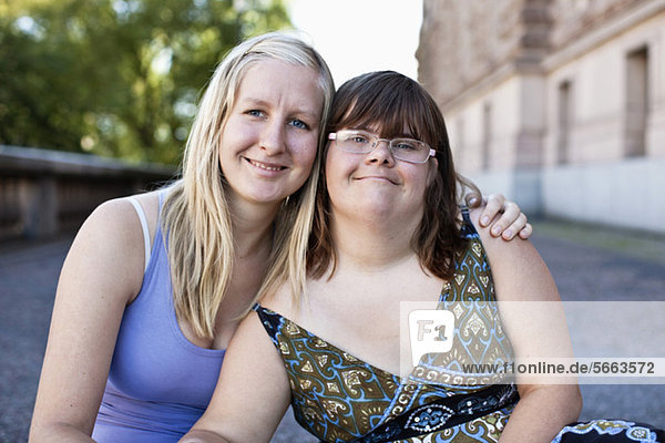 Porträt einer liebenden Frau mit Down-Syndrom und gemeinsam lächelnder persönlicher Assistentin