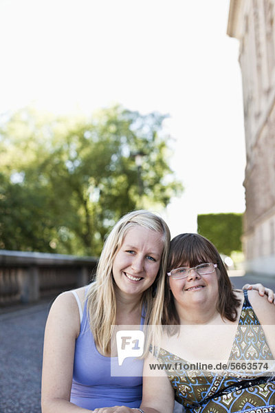 Porträt einer Frau mit Down-Syndrom  die mit einem Freund zusammensitzt.