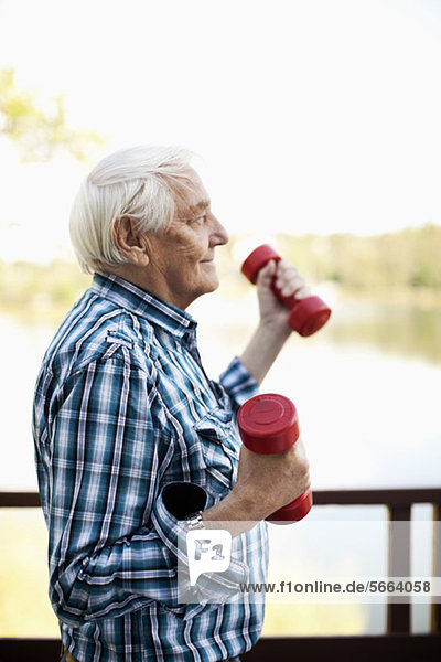 Seitenansicht des älteren erwachsenen Mannes beim Heben des Handgewichts im Freien
