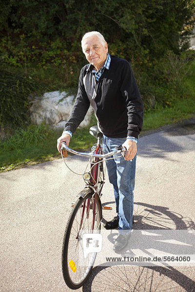 Aktiver Senior mit Fahrrad an einem sonnigen Tag
