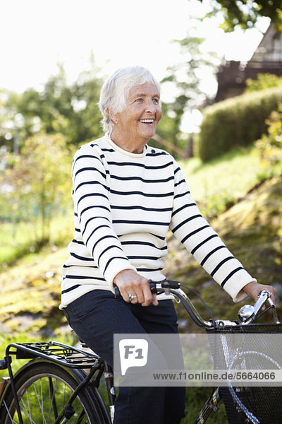 Glückliche Seniorin beim Radfahren im Park