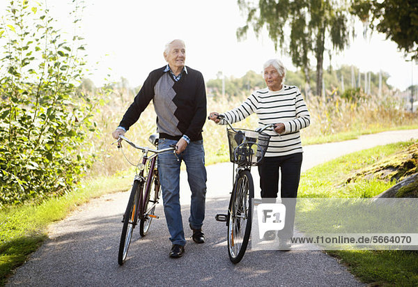 Vorderansicht eines aktiven älteren Paares im Park mit Fahrrädern