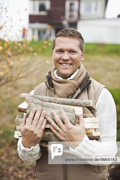 Porträt eines glücklichen Mannes mit Brennholz