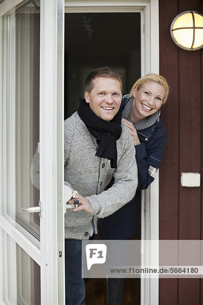 Porträt eines glücklichen Paares  das vor der Haustür steht.