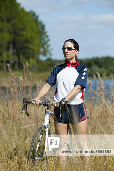 Frau im Gras stehend mit Rennrad  Portrait