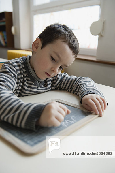 Junge schreibt auf Kreidetafel