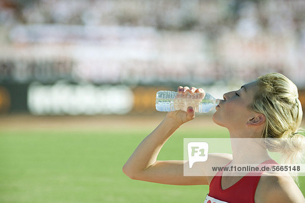 Sportlerin beim Trinken von Wasser in Flaschen