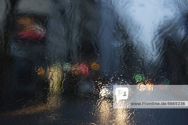 Stadtstraße durch ein regenbedecktes Fenster gesehen
