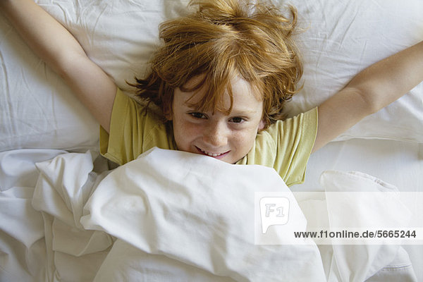 Boy lying in bed with arms outstretched