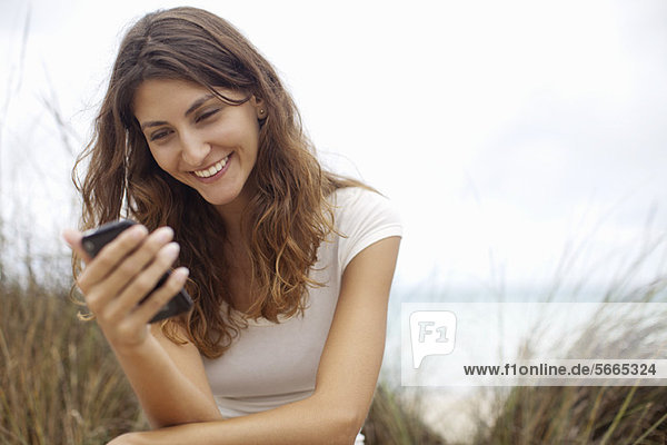 Junge Frau lächelt Handy an