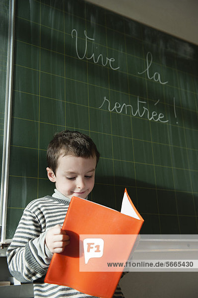 Junge liest vor der Tafel im Klassenzimmer