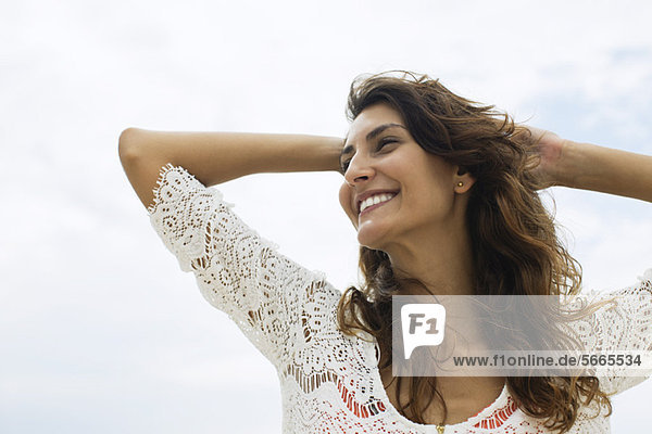 Smiling young woman with hands on head  low angle view
