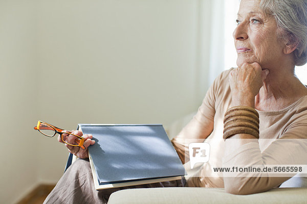 Seniorin sitzend auf Sofa mit Buch
