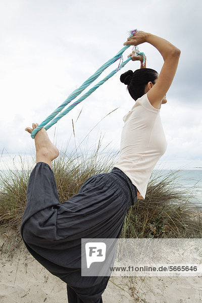 Woman in Natarajasana pose on beach  side view