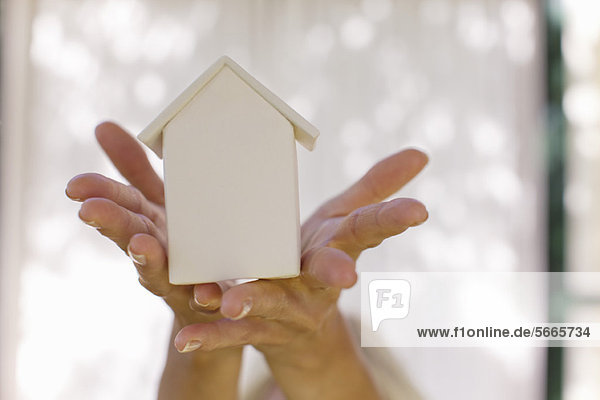 Woman's hands holding small model house  cropped