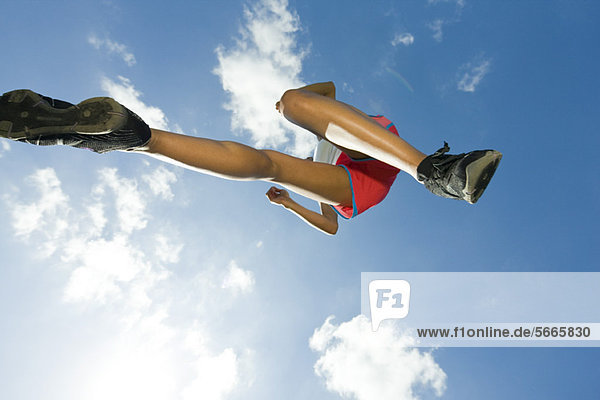 Sportlerin beim Springen in der Luft  direkt darunter