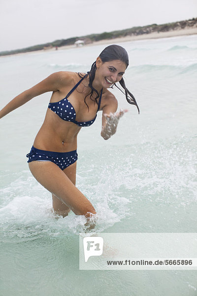 Young woman splashing water in ocean