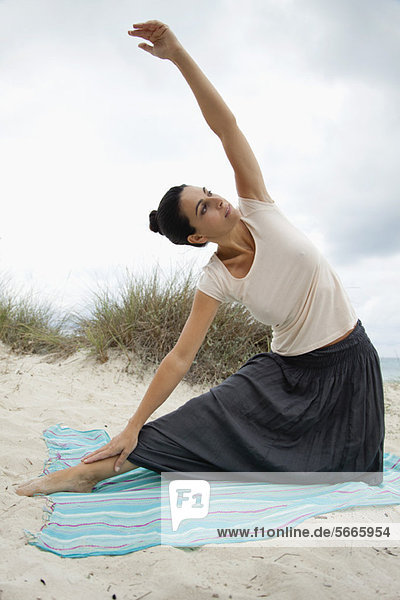 Mature woman doing yoga stretch on beach  portrait