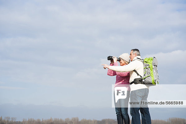 Couple standing outdoors with binoculars