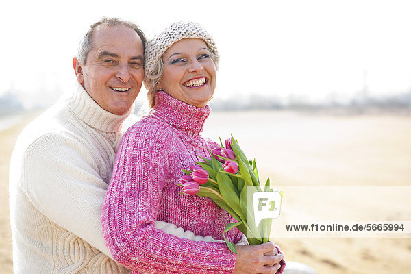 Fröhliches Paar mit Tulpenstrauß im Freien