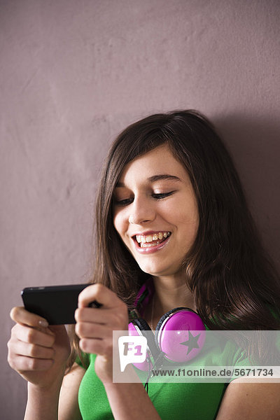 Lachende Teenagerin schaut auf ihr Handy