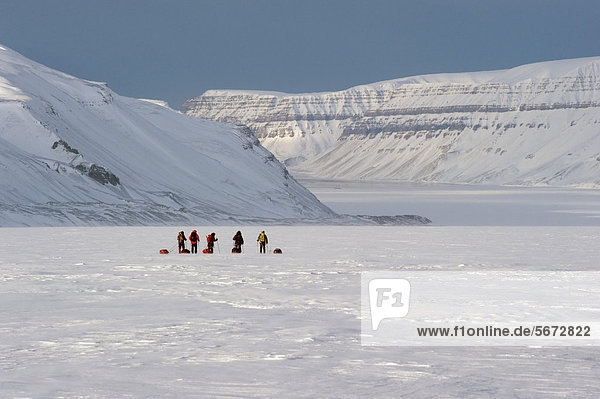 Skiwanderer mit Pulkas beim Abstieg eines Gletschers  hinten das schwimmende Hotel Boat in the Ice im Tempelfjorden  Von Postbreen  Tempelfjorden  Spitzbergen  Svalbard  Norwegen  Europa