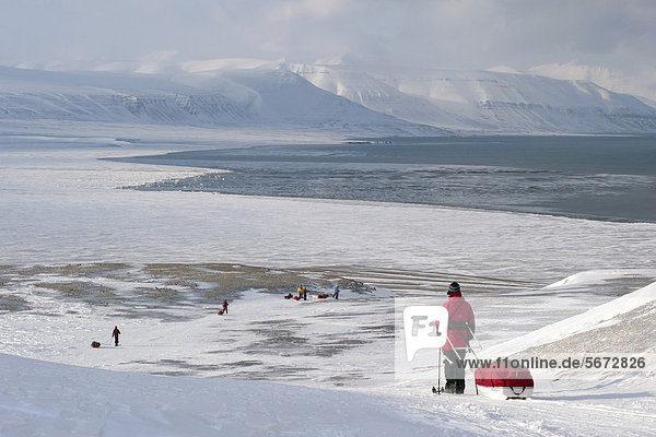 Skiwanderer mit Pulkas bei der Abfahrt zum Fjord Sassenfjorden  Teil des Isfjorden  bei Fredheim  im Winter  Spitzbergen  Svalbard  Norwegen  Europa