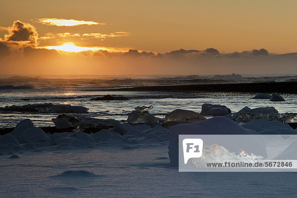 Sonnenuntergang vor den schneebedeckten Eisbergen am Atlantikstrand bei Jökuls·rlÛn  Vatnajökull Nationalpark  Island  Europa